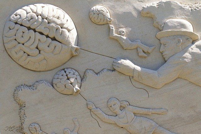 sand sculpture of girl and man holding balloons shaped like a brain