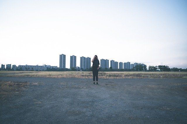 woman standing alone in an empty lot near buildings because of anxiety