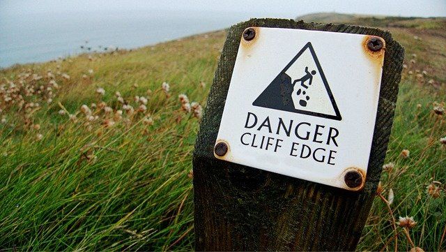 sign on cliff warning about risk of falling off cliff for summertime anxiety is real