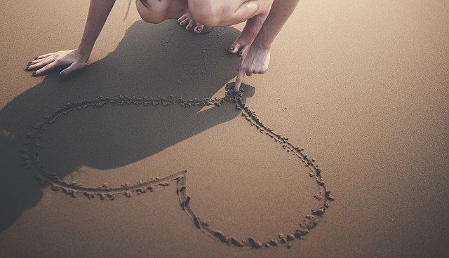 person drawing heart in sand for how to deal with summertime anxiety