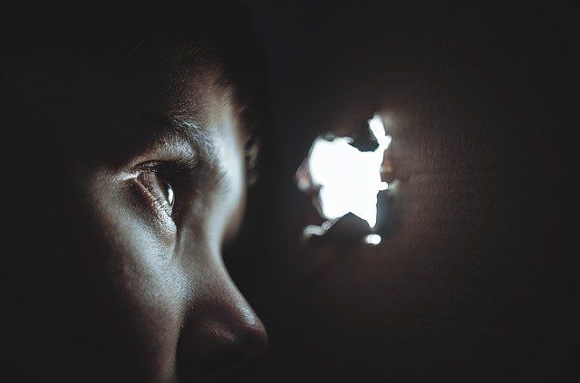 person looking outside through hole in the wall at common OCD symptoms