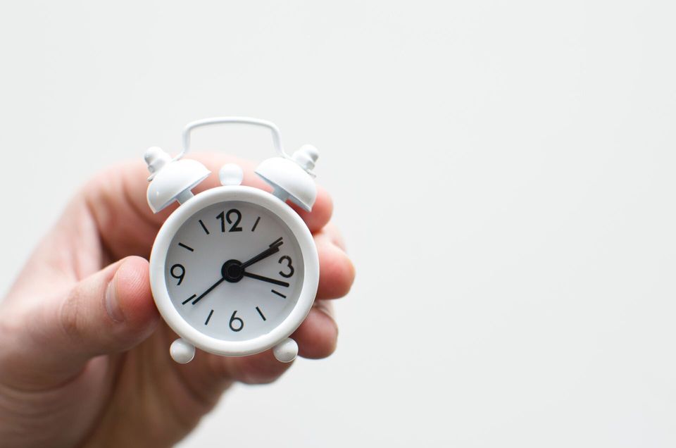 hand holding small alarm clock for focusing on short term priorities
