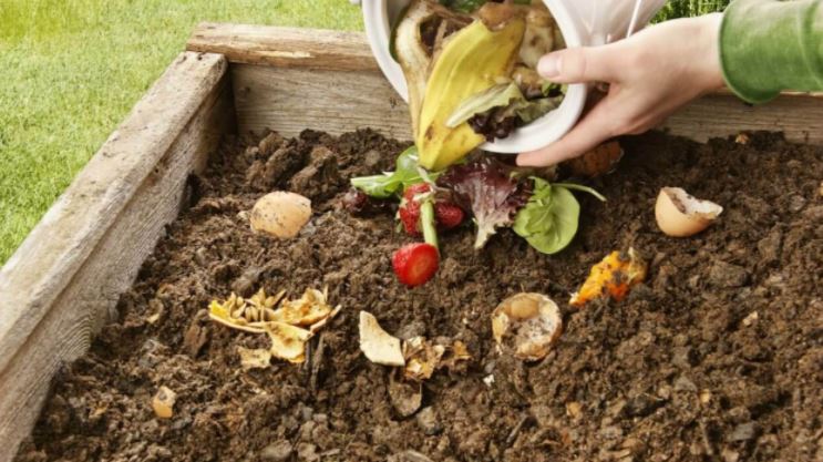 person making their own compost for growing a vegetable garden