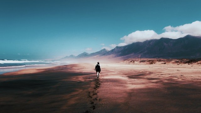 person walking alone on beach because of summer anxiety and depression