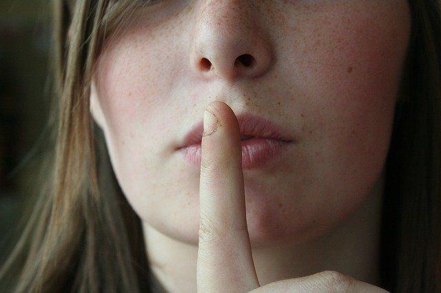 woman holding finger to lips because of OCD symptoms no one talks about