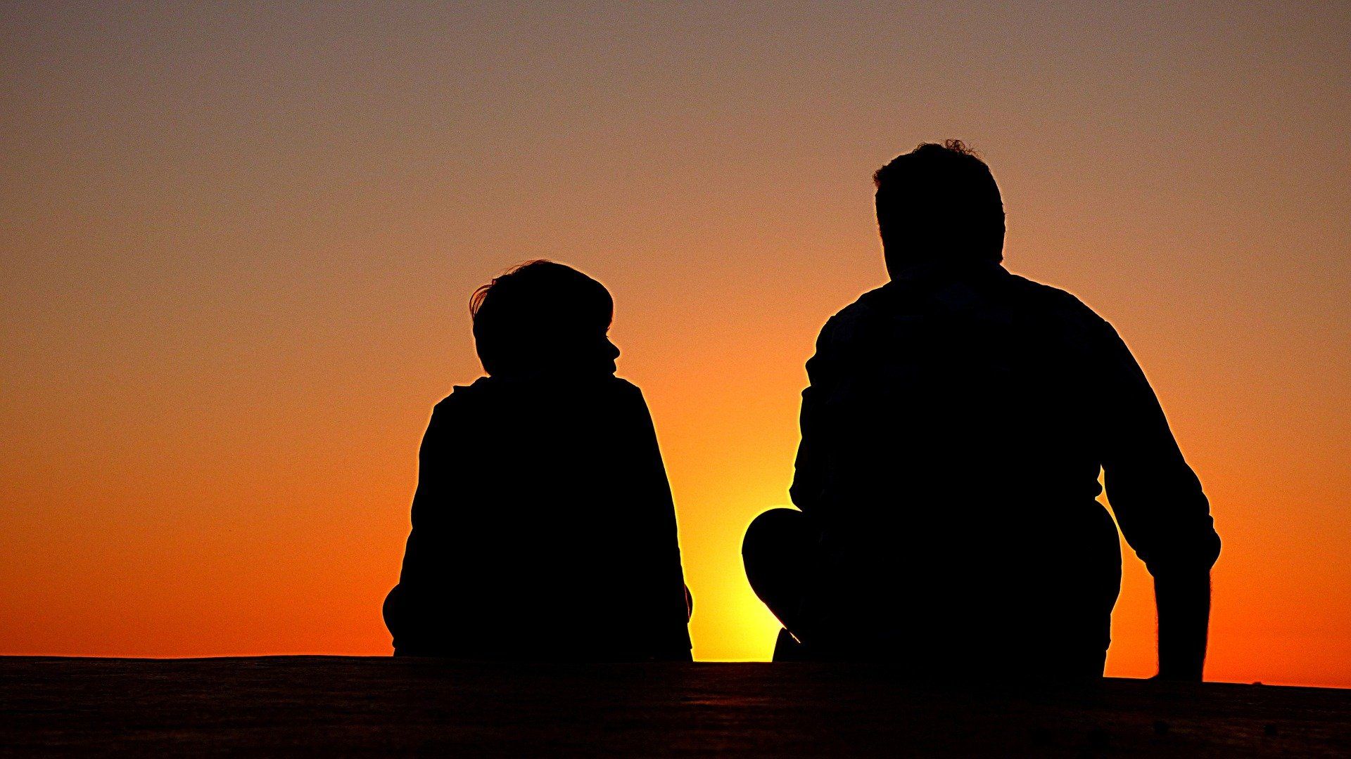 man and boy sitting on ground during sunset to help boy manage anxiety