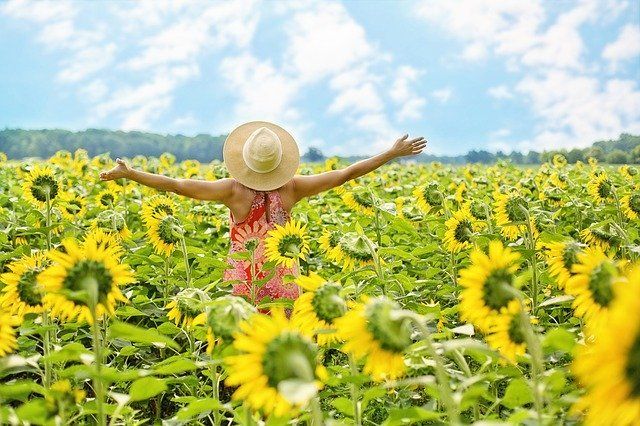 woman raising her arms in field of sunflowers because taking steps to manage anxiety and depression