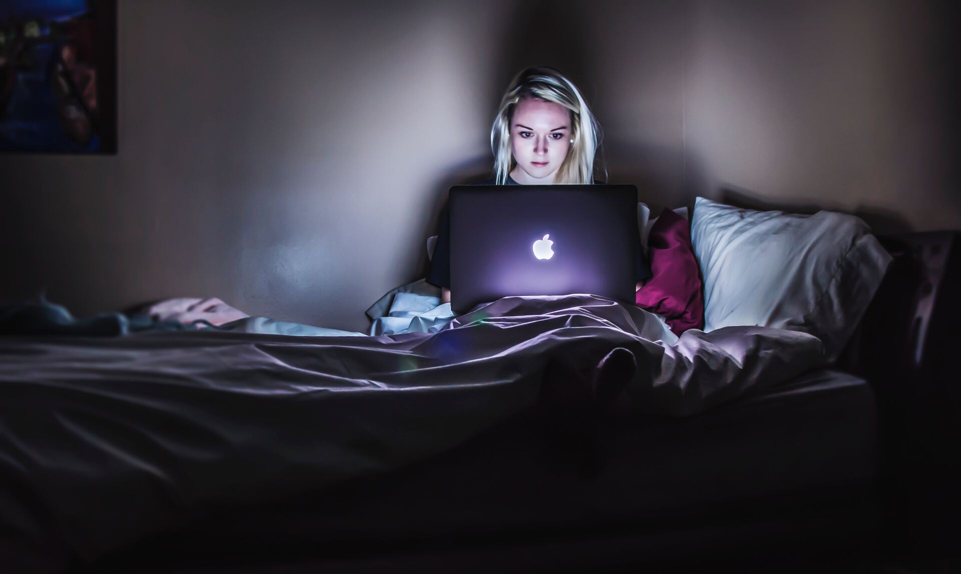woman sitting in bed looking at lap top to see if having another type of OCD would be easier
