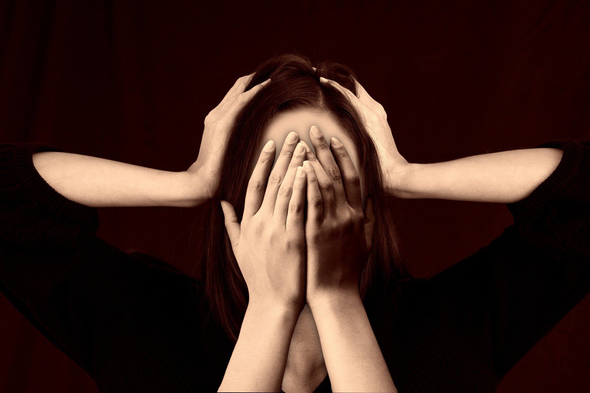 woman with hands on side of her head and another set of hands covering her face for two parts of OCD