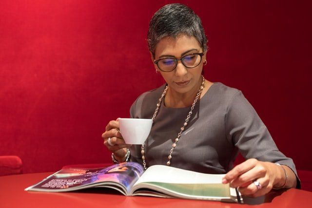 woman at a table reading a magazine is simple self care