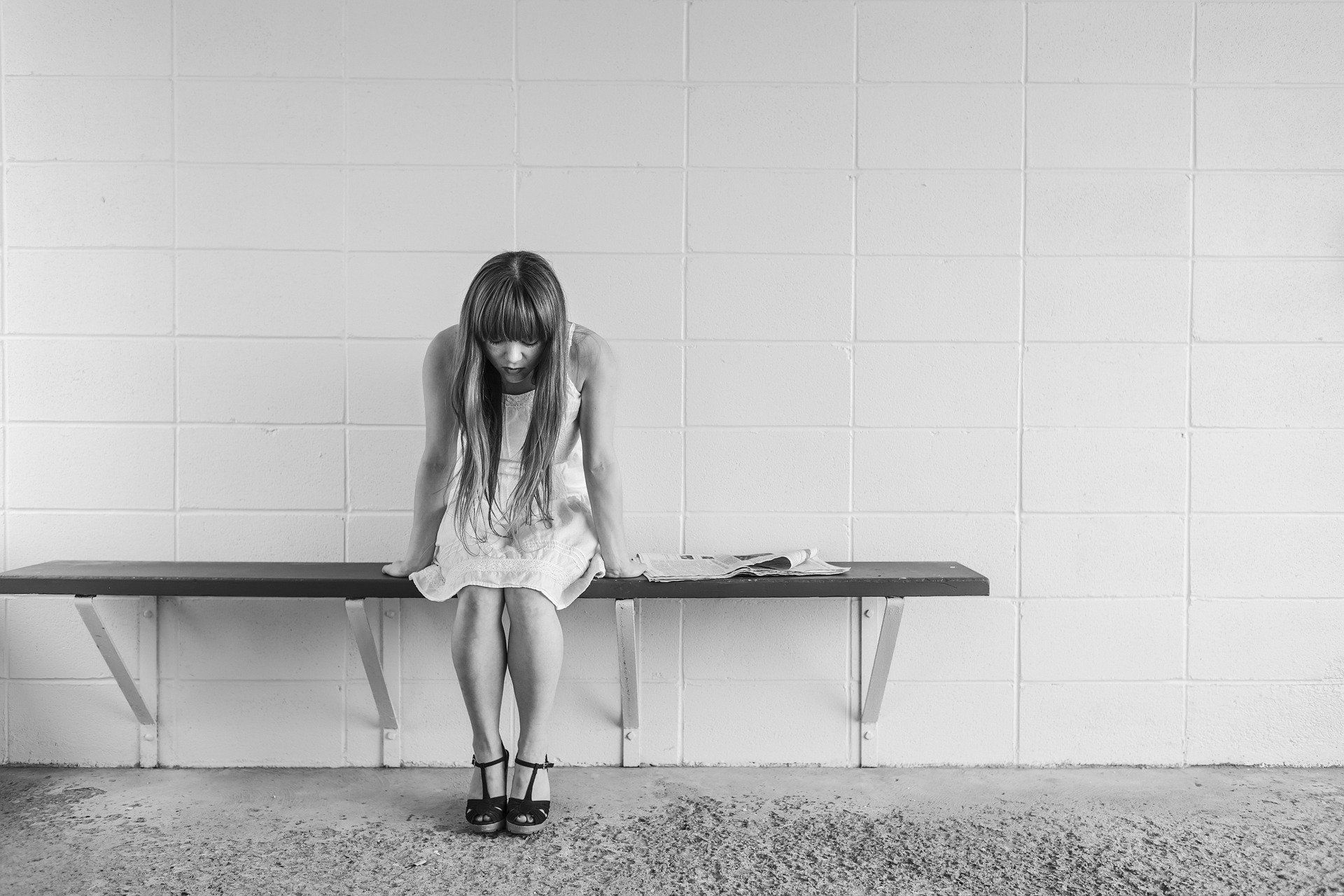young woman sitting on bench looking down at her feet because of anxiety disorders