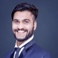 Arpit Toshniwal with a beard is wearing a suit and tie and smiling.