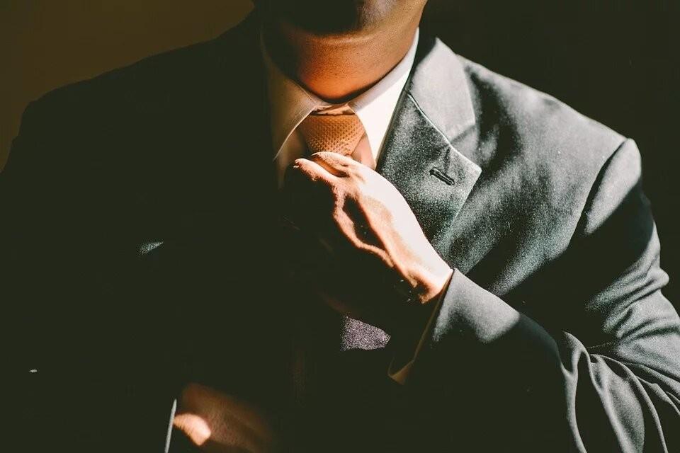 A man in a suit and tie is adjusting his tie.