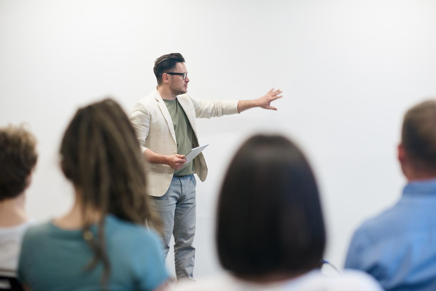 A man is giving a presentation to a group of people in a classroom.