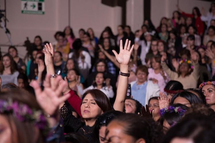 A crowd of people are raising their hands in the air.