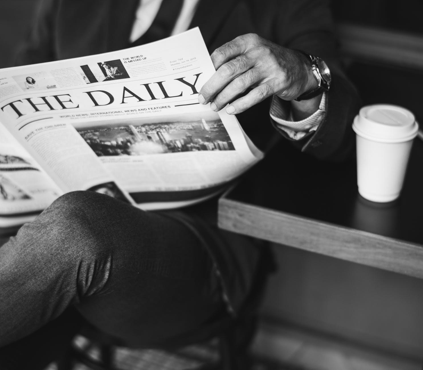 A man sits at a table reading the daily newspaper