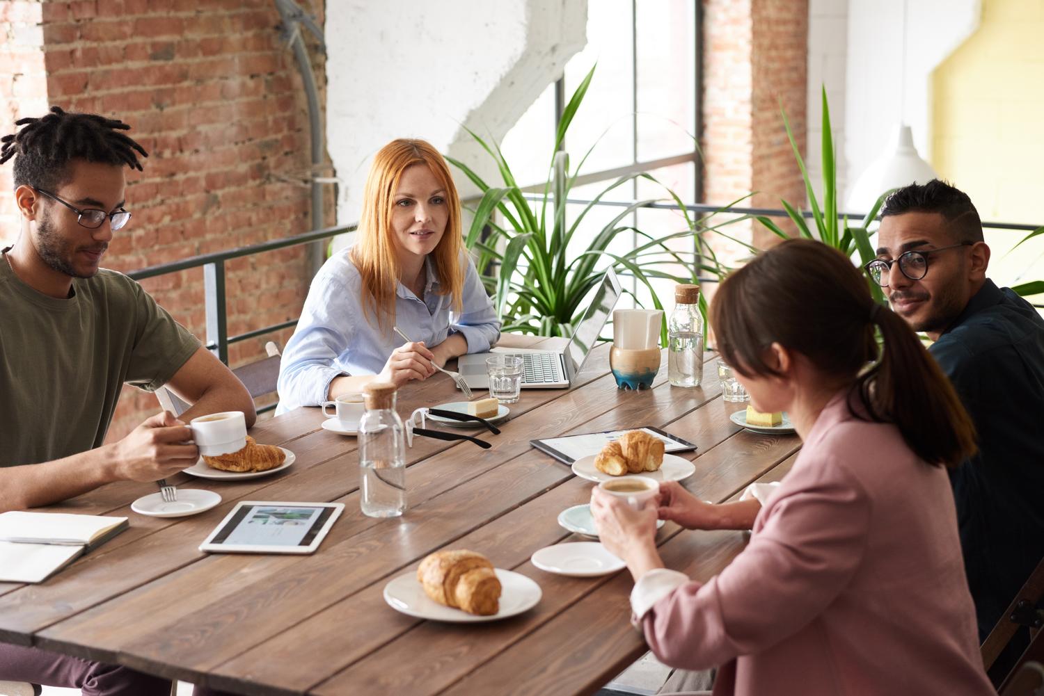 A group of people are sitting around a wooden table eating food.