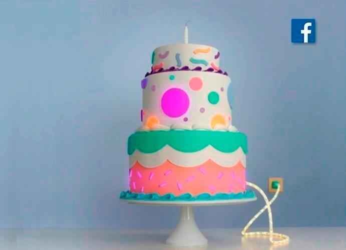 A birthday cake with a facebook logo in the background