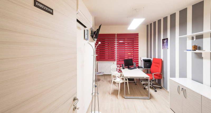 Modern office meeting room with white table, red chairs, and red blinds by a glass wall