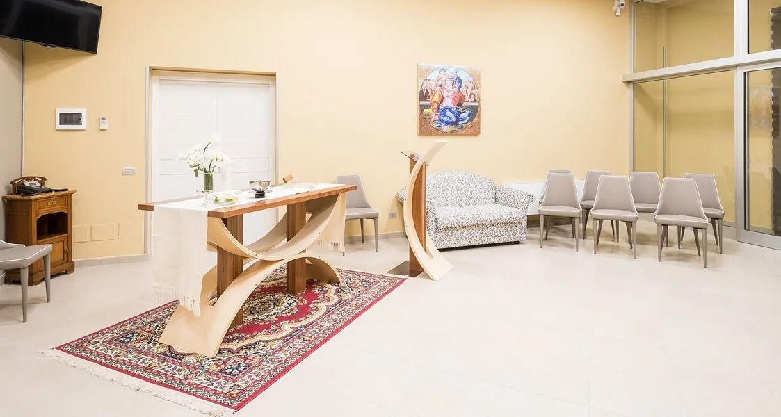 Bright prayer room with altar, chairs, rug, and wall art on beige walls