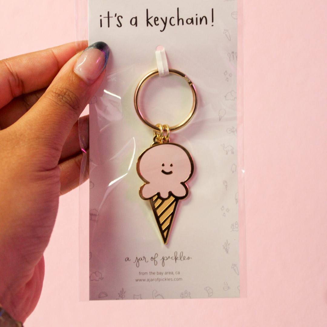 A person is holding a keychain with an ice cream cone on it