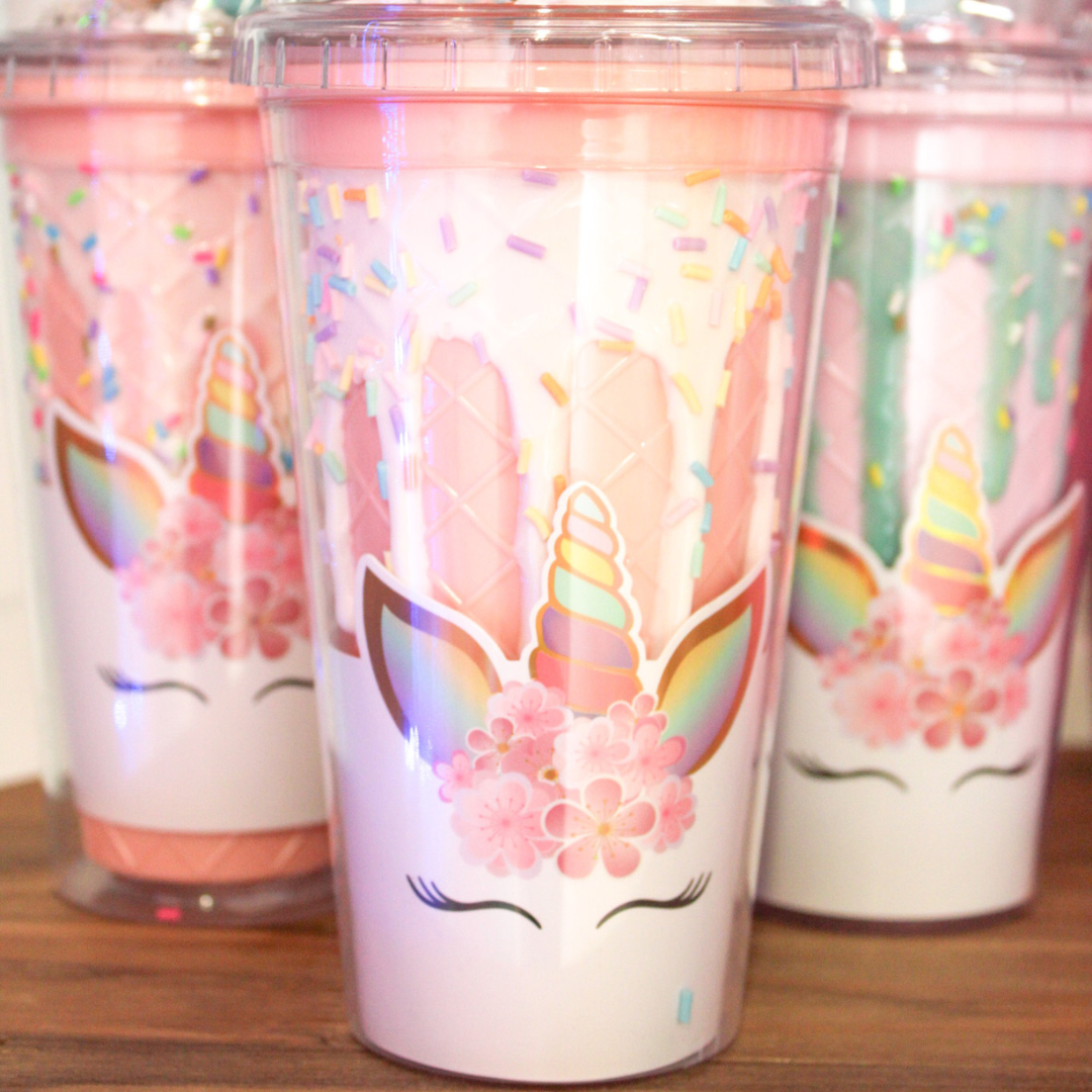 Three cups with unicorns on them are sitting on a wooden table.