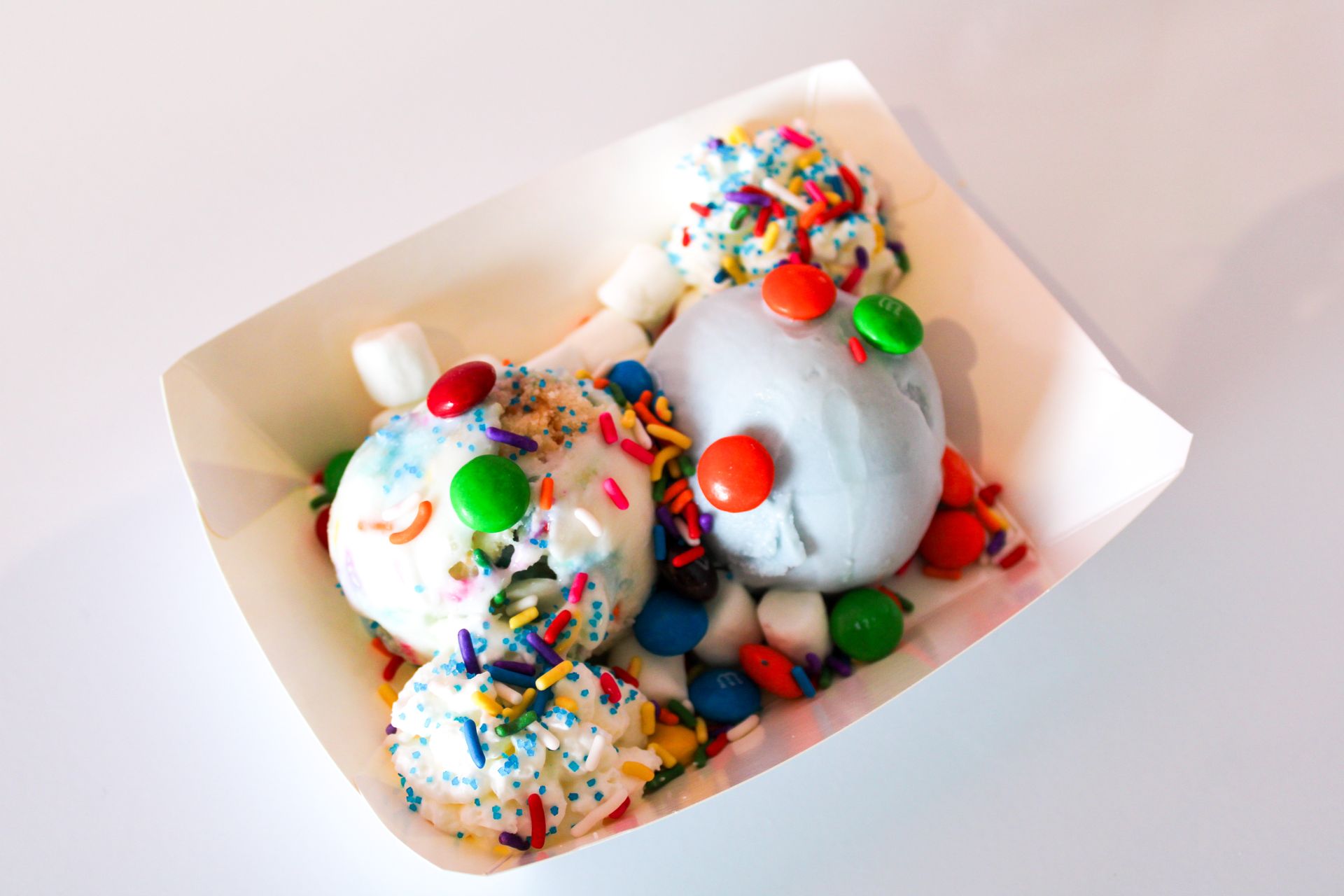 A paper container filled with ice cream and sprinkles.