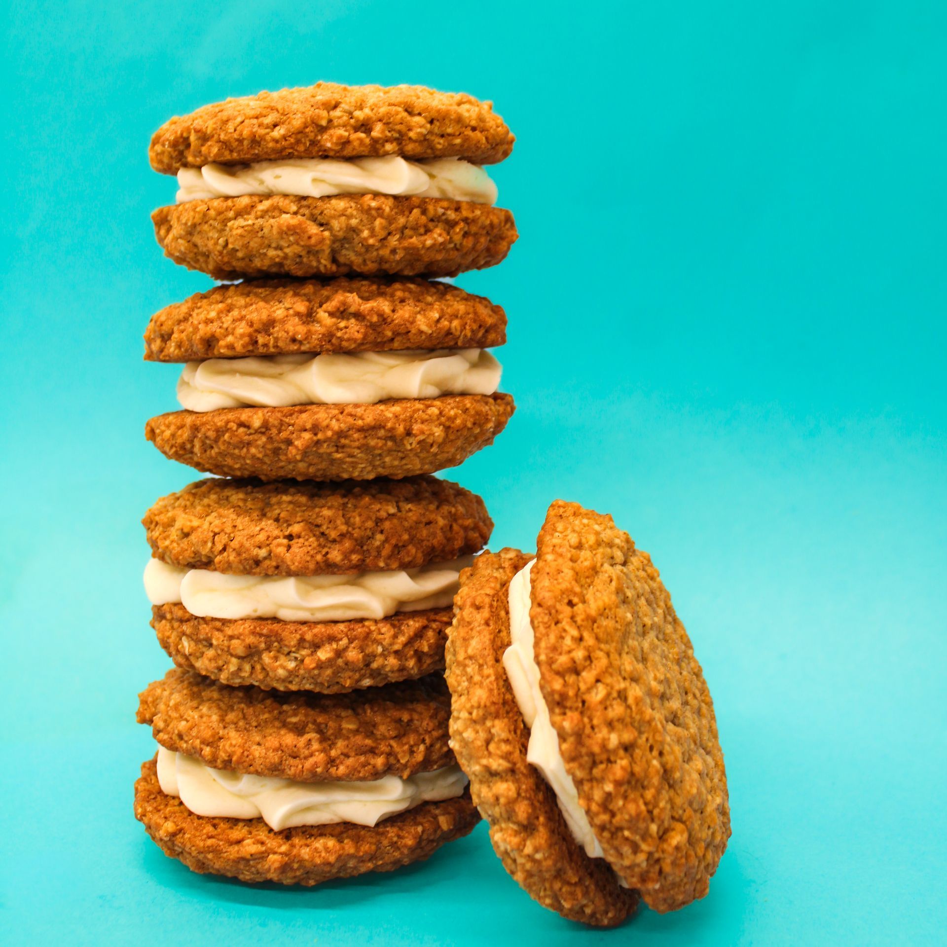 A stack of oatmeal cookies with cream cheese frosting on a blue background