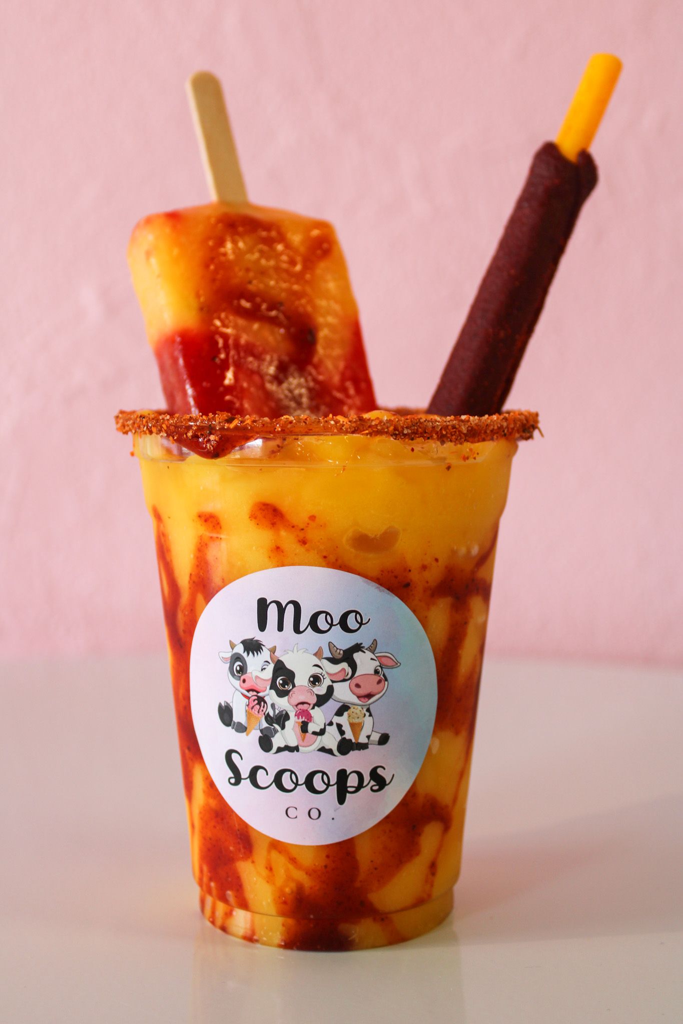 A cup of moo scoops with two popsicles in it