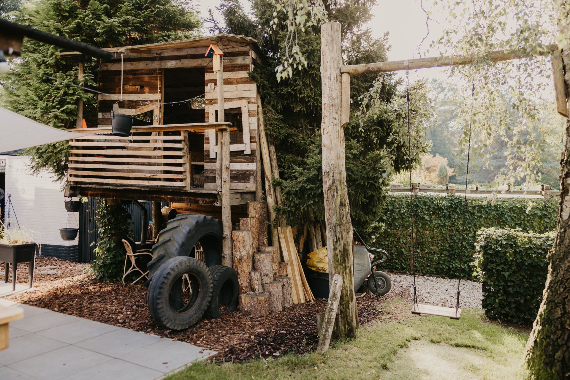 Een boomhut gemaakt van banden in een achtertuin.