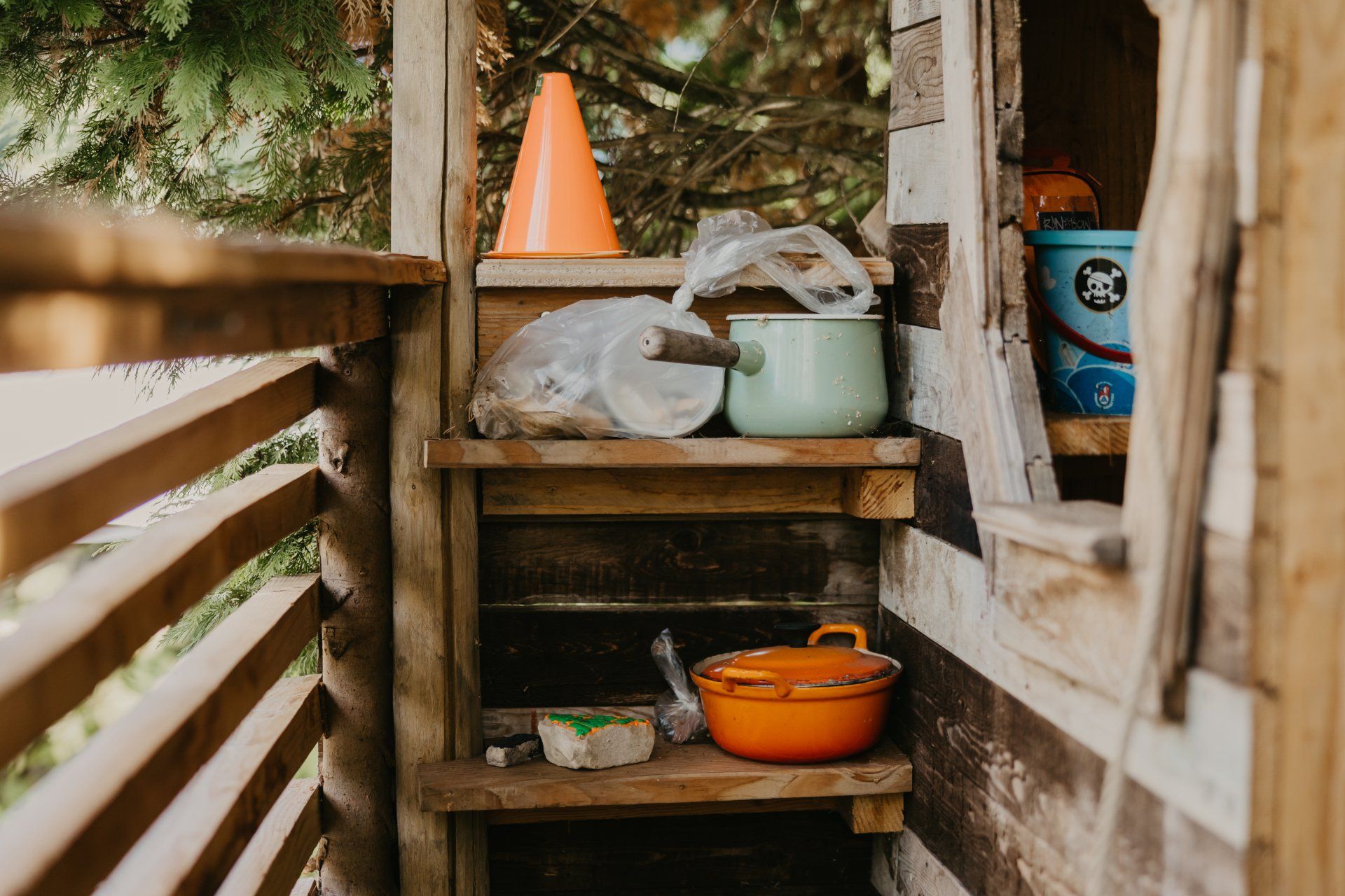 Een houten trap die leidt naar een houten plank met potten en pannen erop.