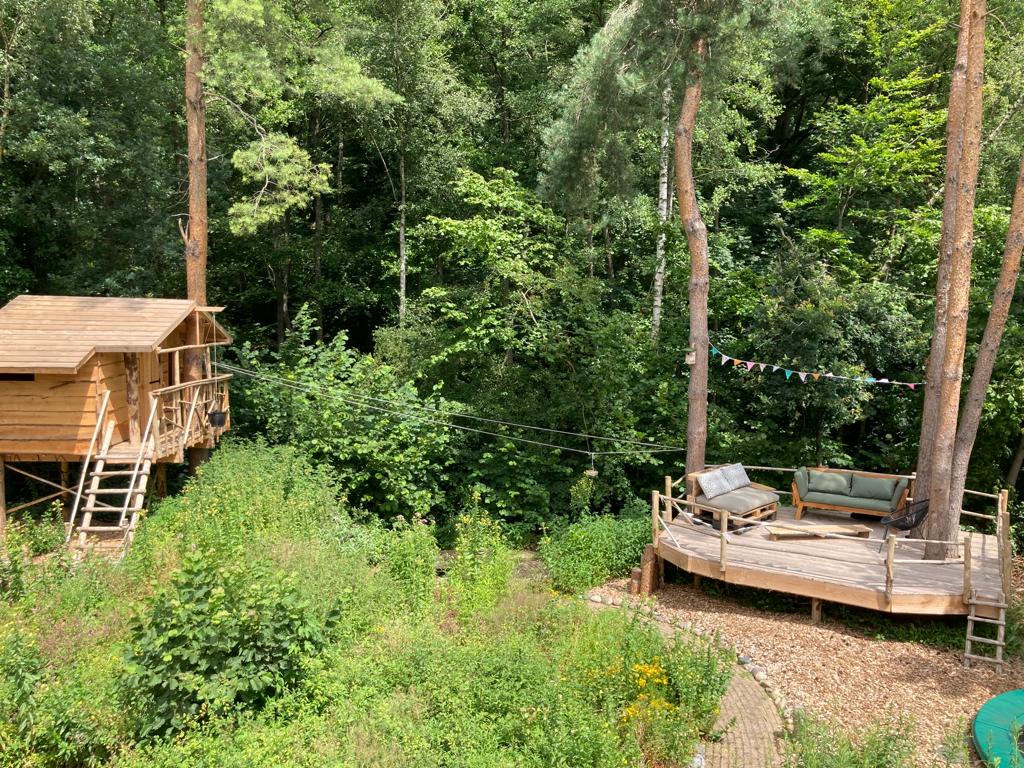 Een boomhut met een terras midden in een bos.