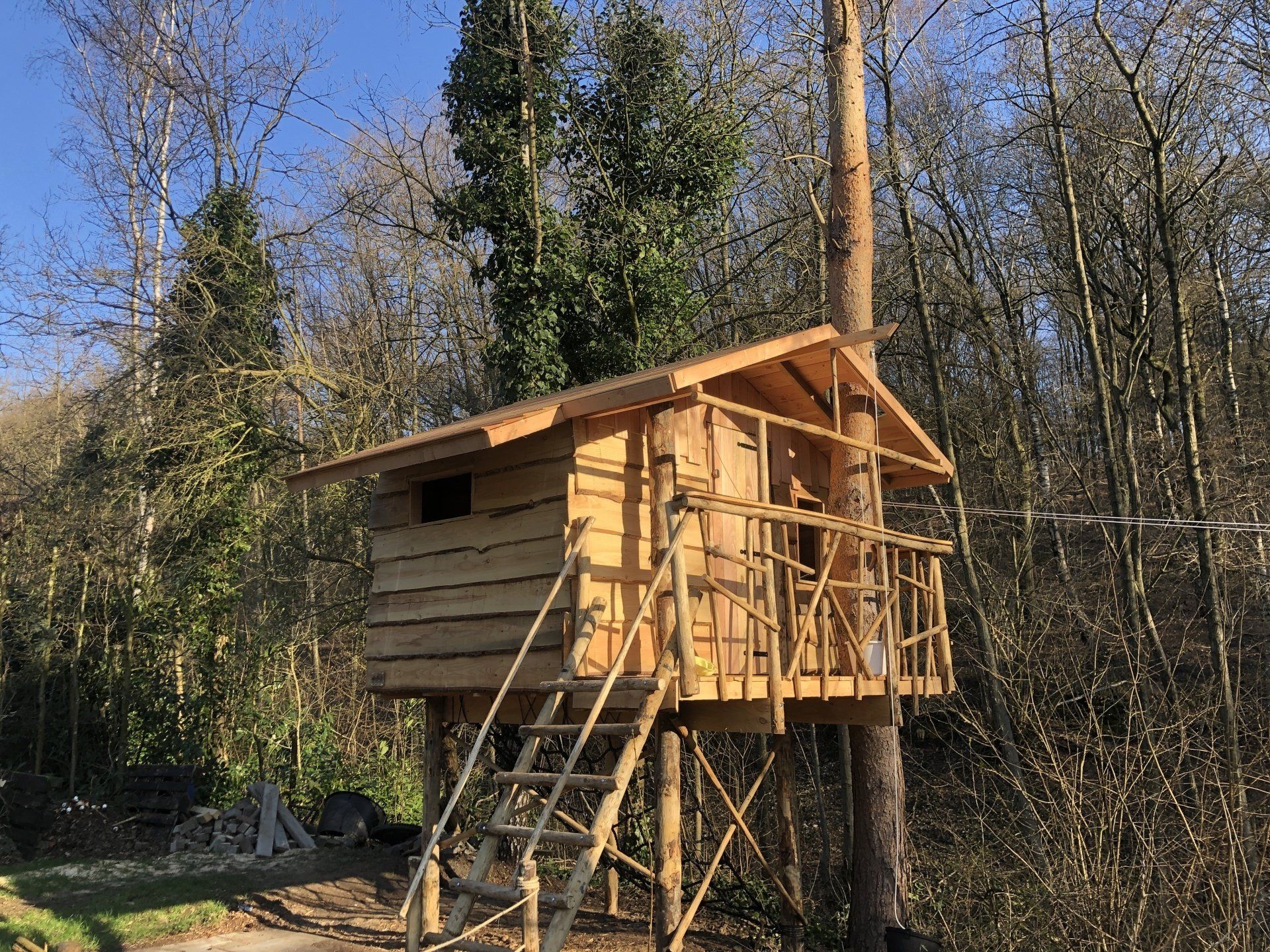 Een kleine houten boomhut midden in een bos.