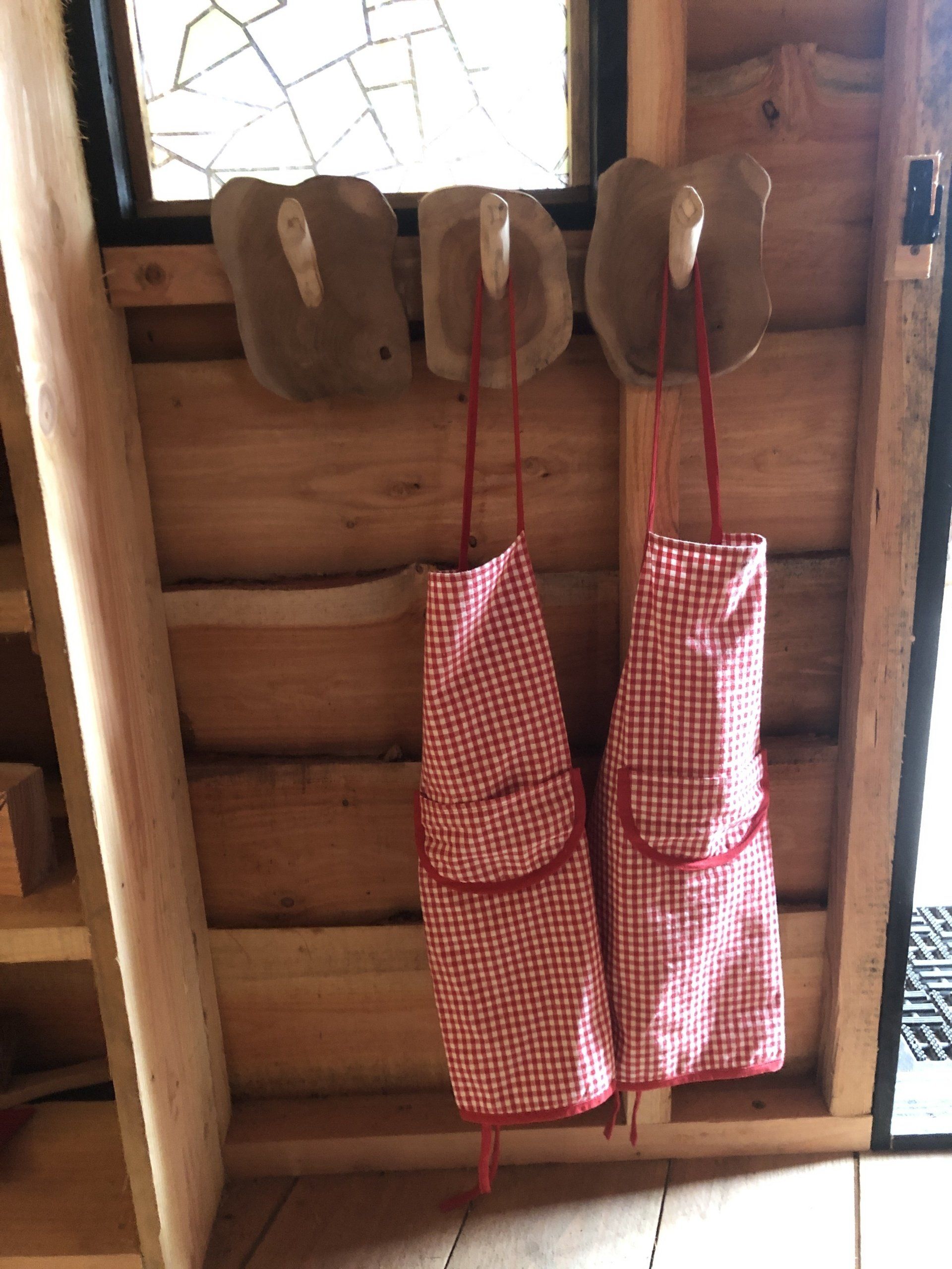 Aan een houten muur hangen twee rood-witte schorten.