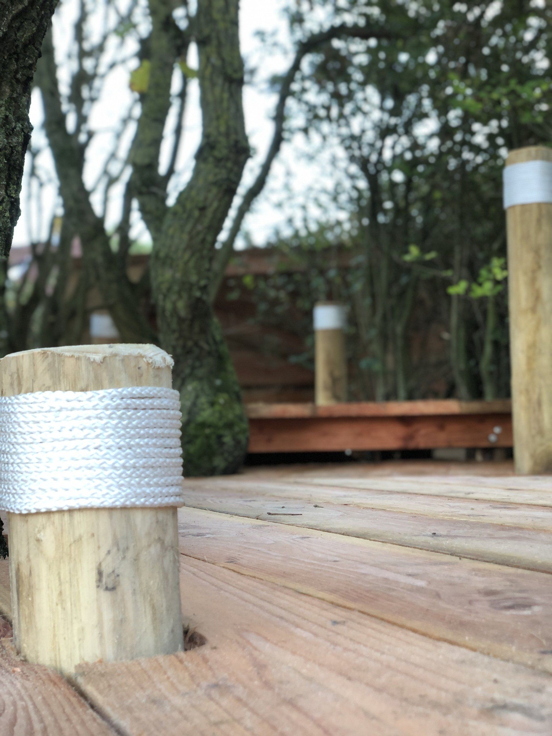 Een houten dek met een touw om een ​​houten paal gewikkeld.