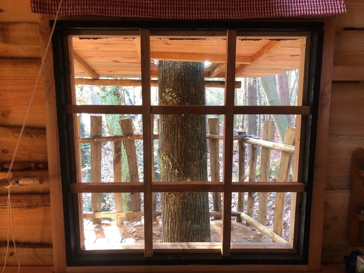Een raam in een blokhut met uitzicht op een boom