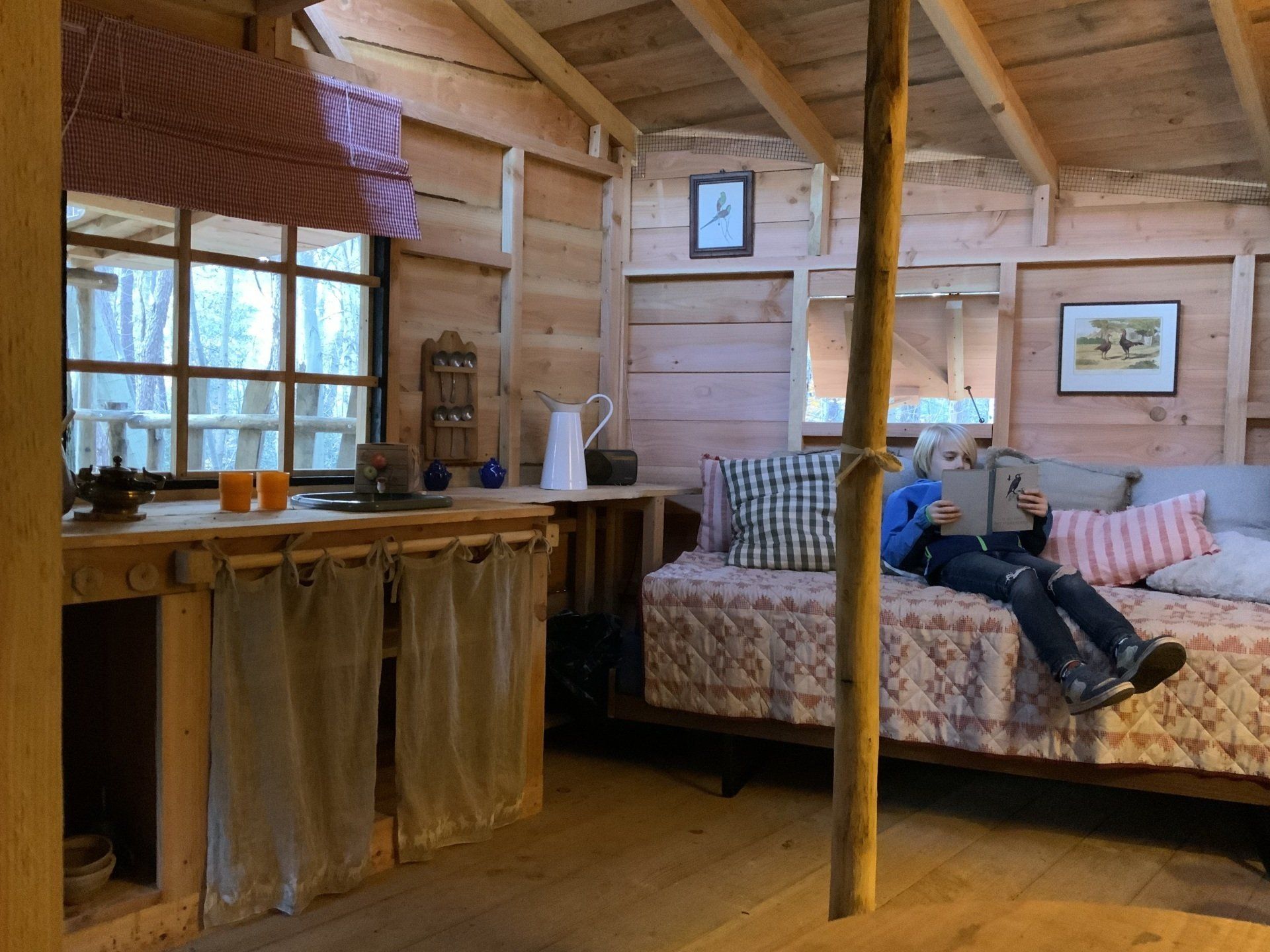 Een persoon die op een bed ligt in een houten hut