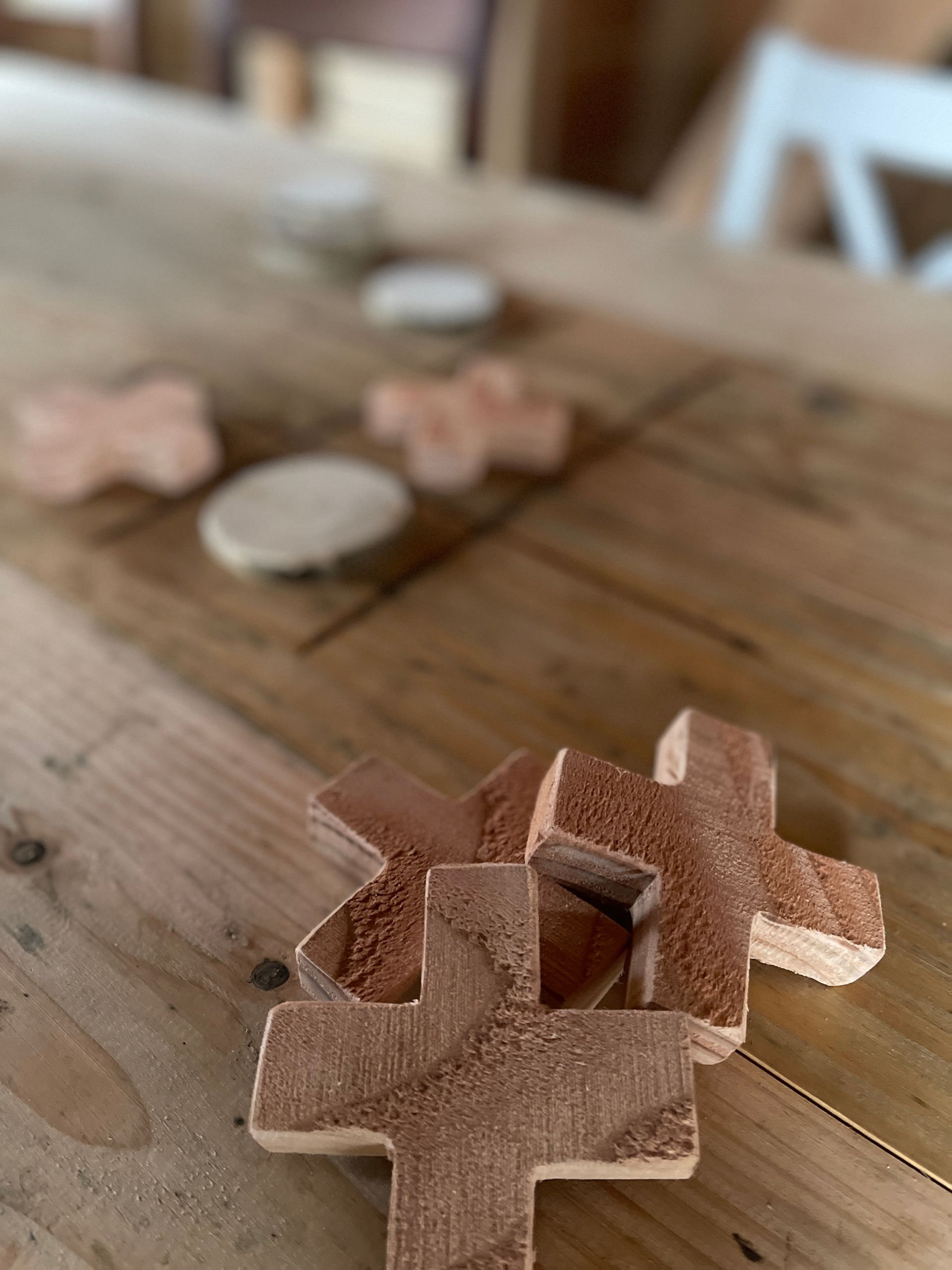 Op een houten tafel staat een houten kruis.