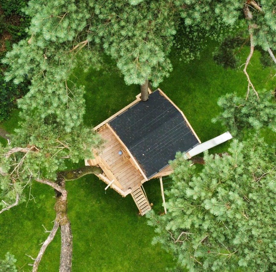 Een luchtfoto van een boomhut omgeven door bomen