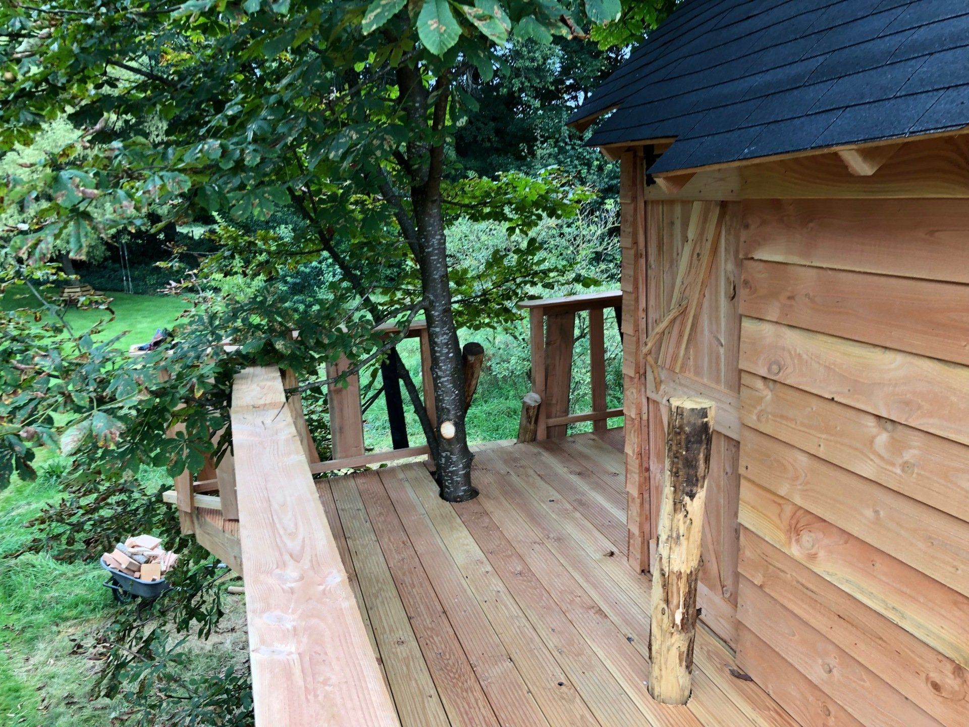 Een houten terras met een trap die naar een boomhut leidt.