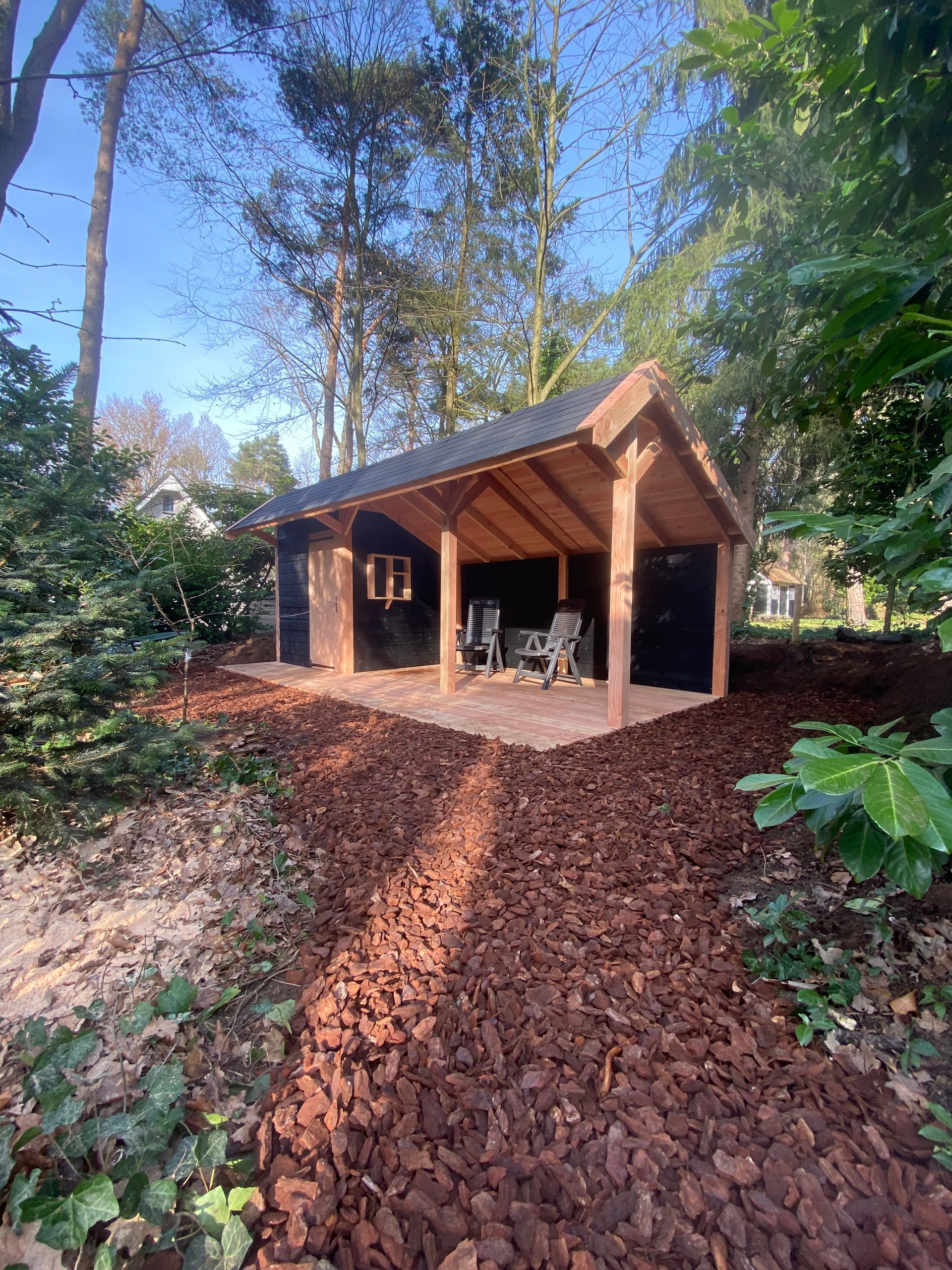 Een houten schuur midden in een bos omringd door bomen.