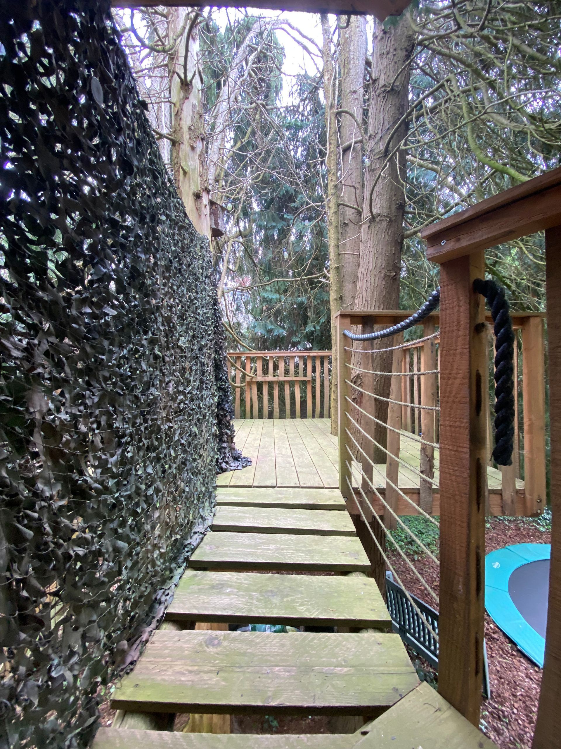 Een houten brug die leidt naar een boomhut in het bos.