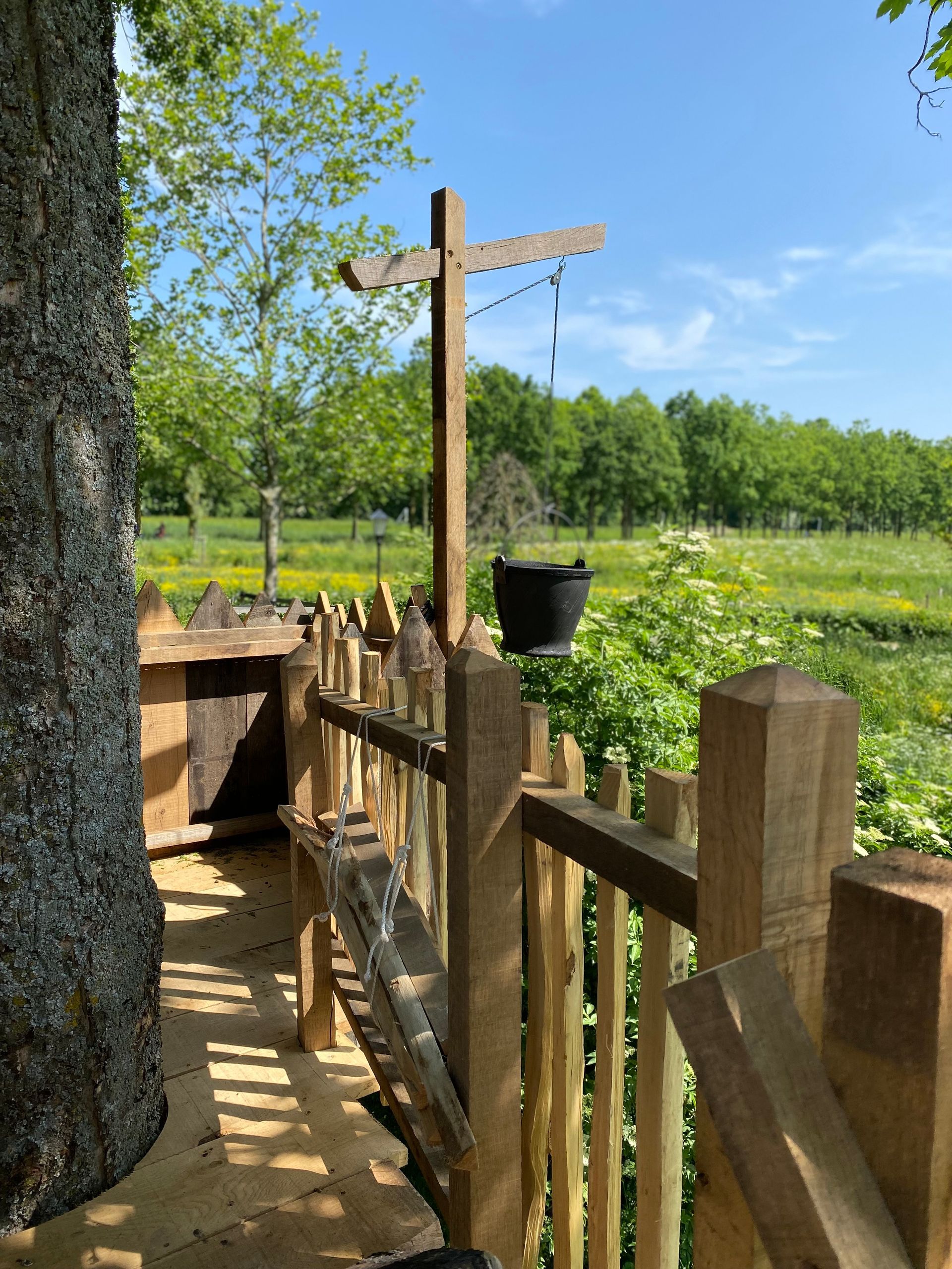 Een houten hek is omgeven door bomen en een veld.