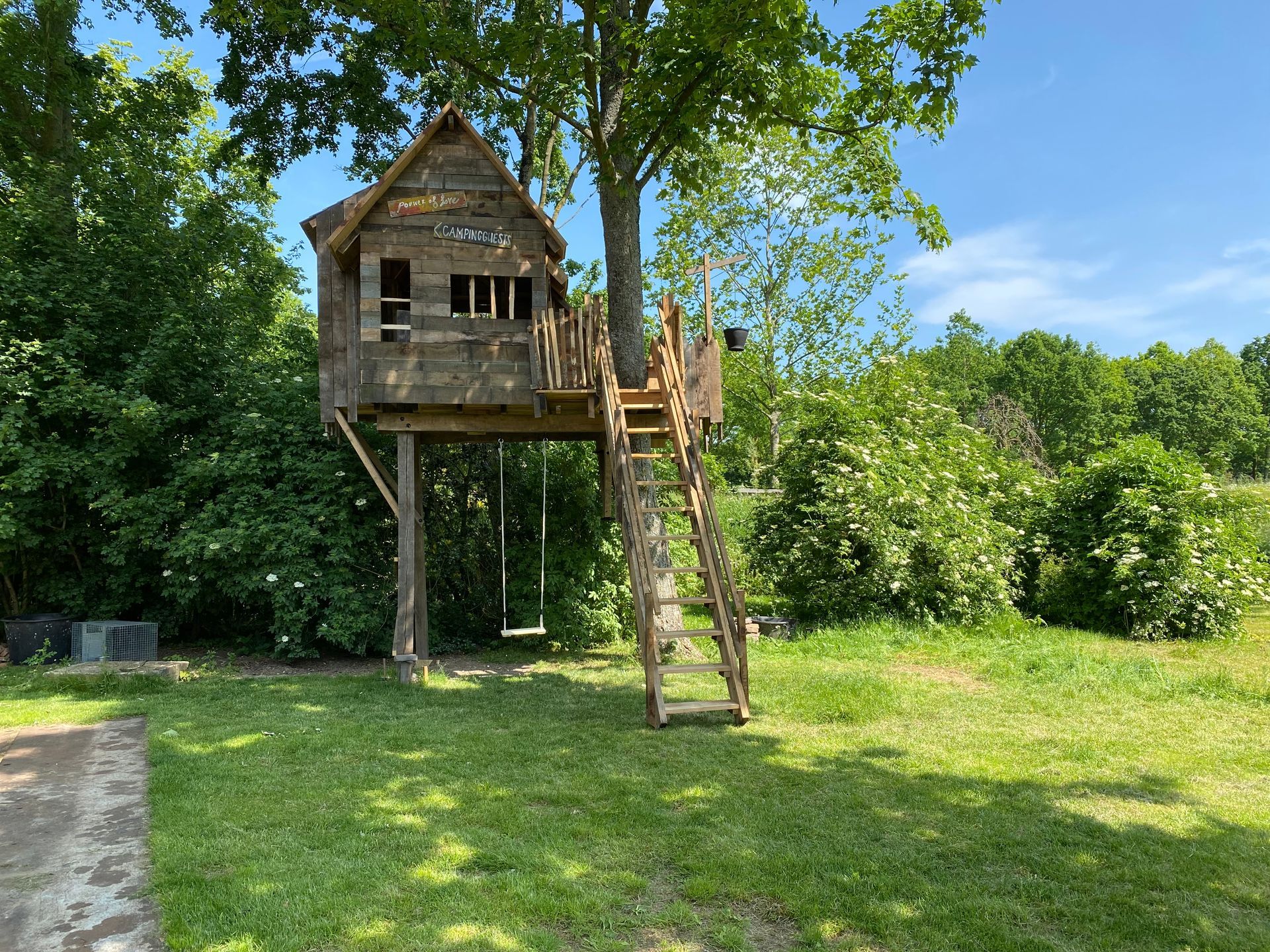 Een boomhut staat bovenop een weelderig groen veld.