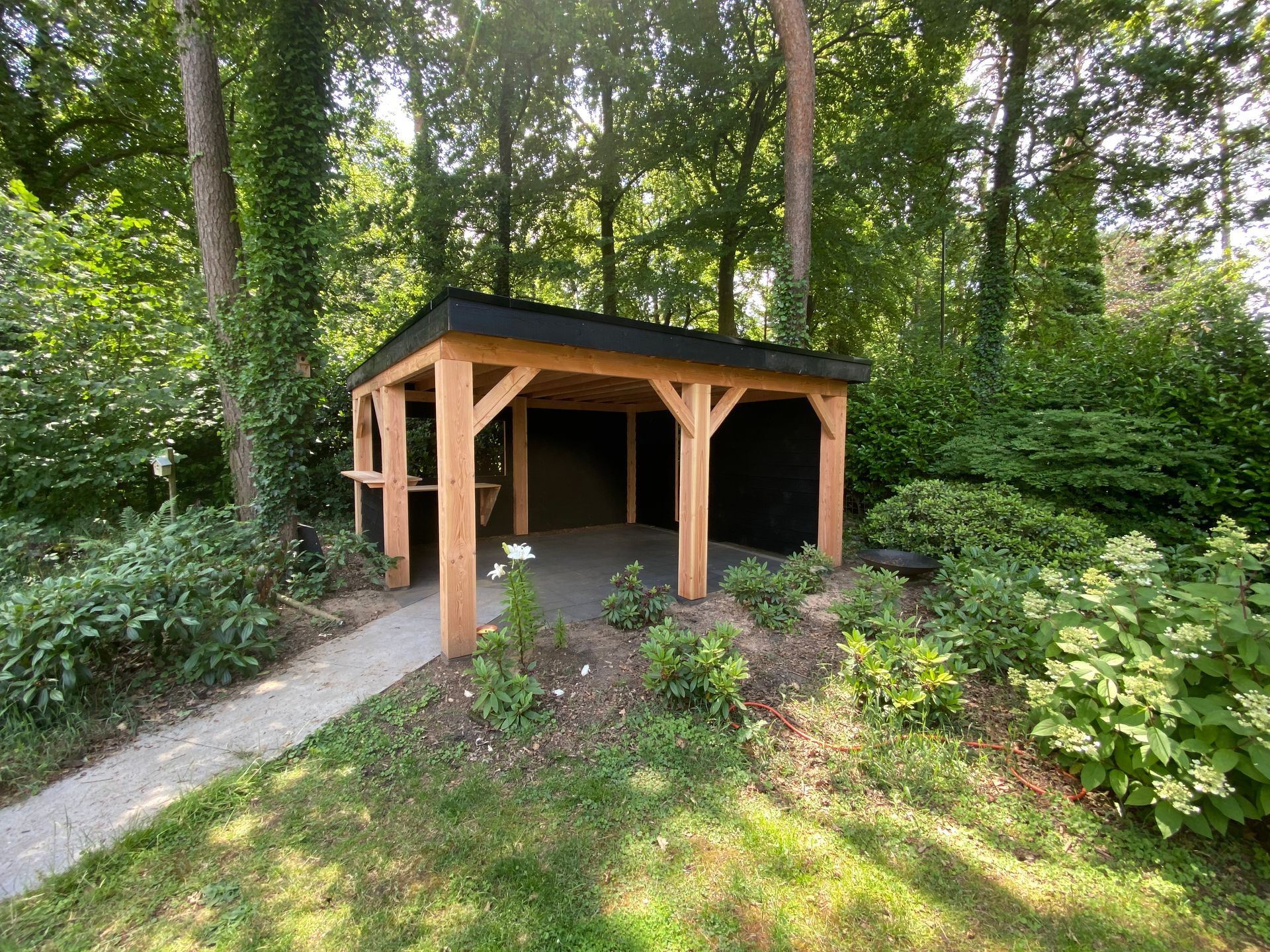 Midden in een weelderig groen bos staat een houten tuinhuisje.