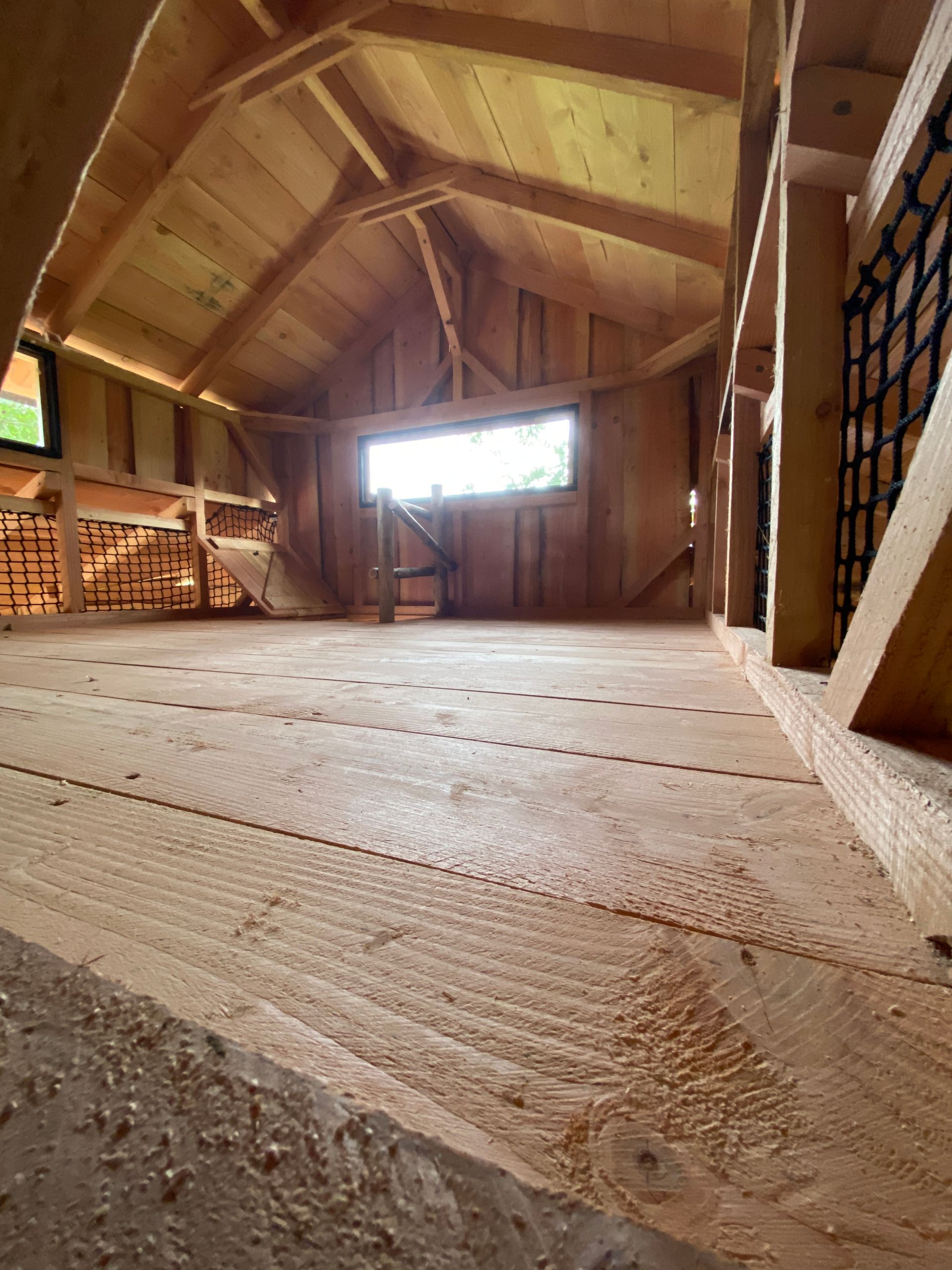 Een houten kamer met een trap en een raam.