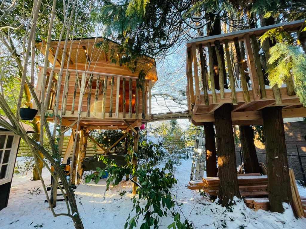 Een boomhut midden in een besneeuwd bos.