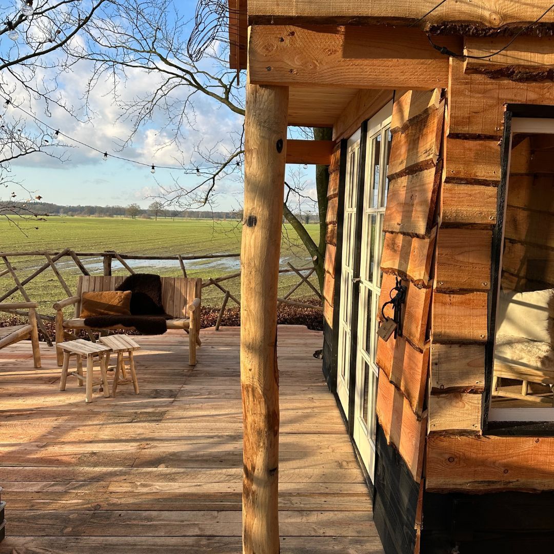 Een houten huis met een veranda en uitzicht op een veld.