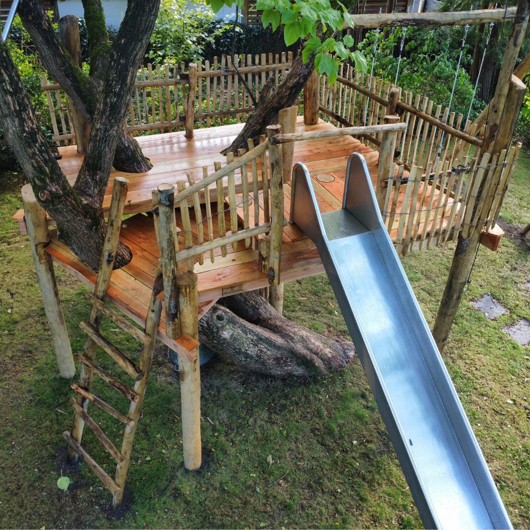Een houten boomhut met glijbaan en trap