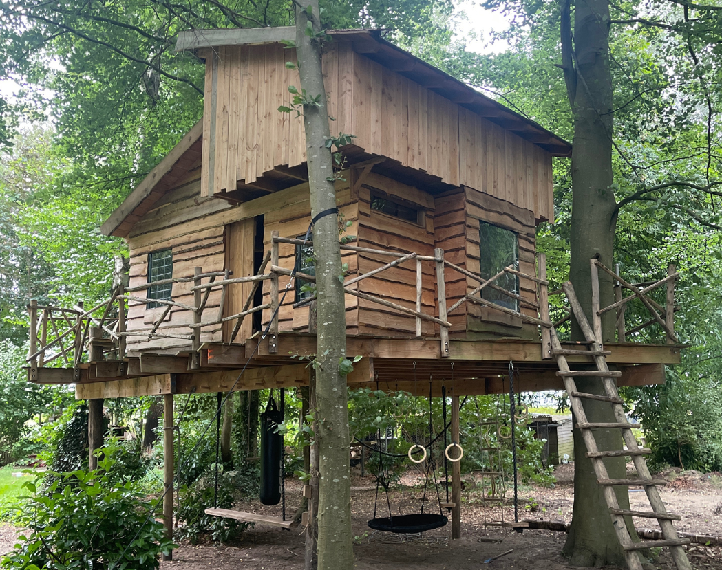 Een houten boomhut midden in een bos.